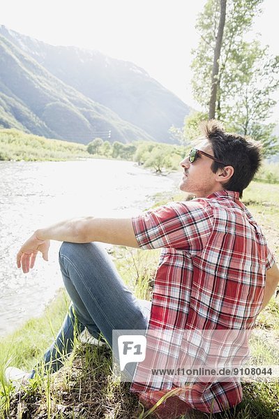 Young man sitting on Toce riverbank  Piemonte  Italy