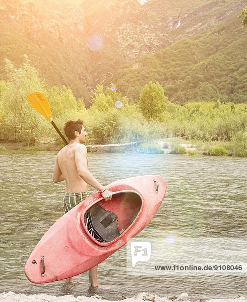 Young man with canoe on Toce riverbank  Piemonte  Italy