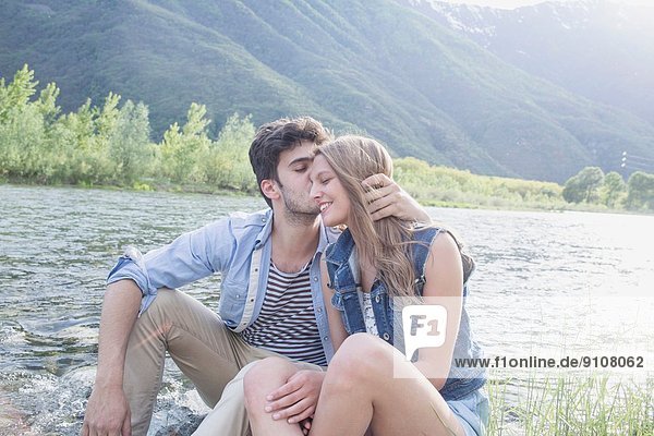 Junger Mann küsst Freundin am Toce Flussufer  Piemonte  Italien