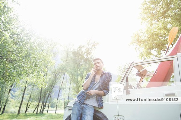 Young man leaning against off road vehicle