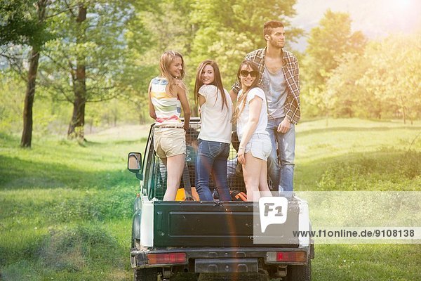 Friends standing on back of off road vehicle