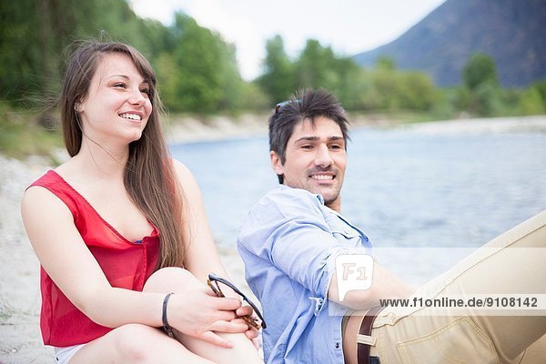 Junges Paar am Fluss sitzend