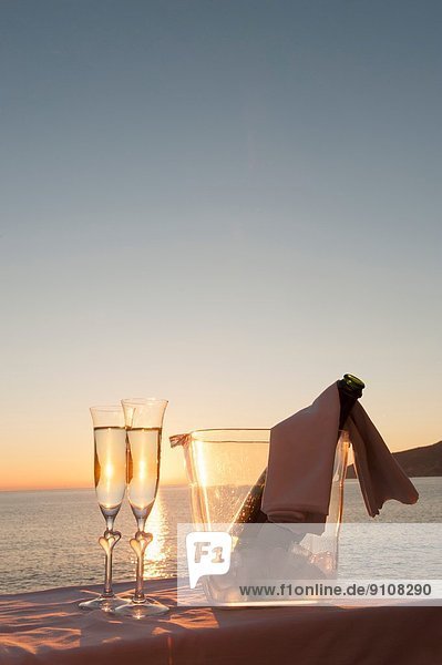 Champagnerflöte und Eimer gegen Sonnenuntergang