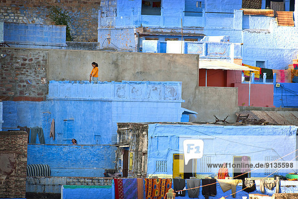 A girl walks along her roof in the Blue City  Rajasthan State  Jodhpur India