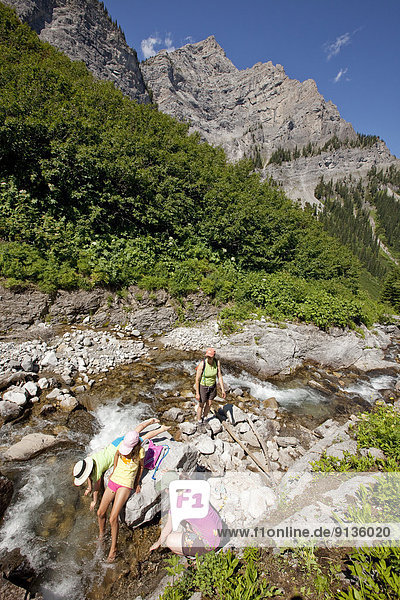 Two young families rest in stream on Mountain Lakes Trail near Fernie  BC  Canada.