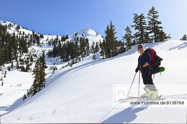 A skier pauses on the trail to Edwards Lake cabin enroute to Mt. Steele cabin in Tetrahedron Provincial Park on the Sunshine Coast of British Columbia Canada. No Model Release