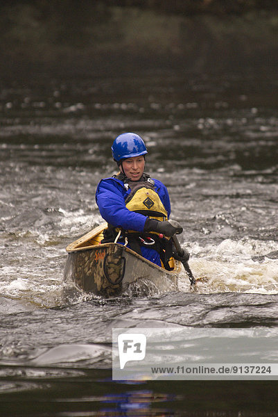 Solo woman whitewater canoeing on the Black River in Muskoka Ontario