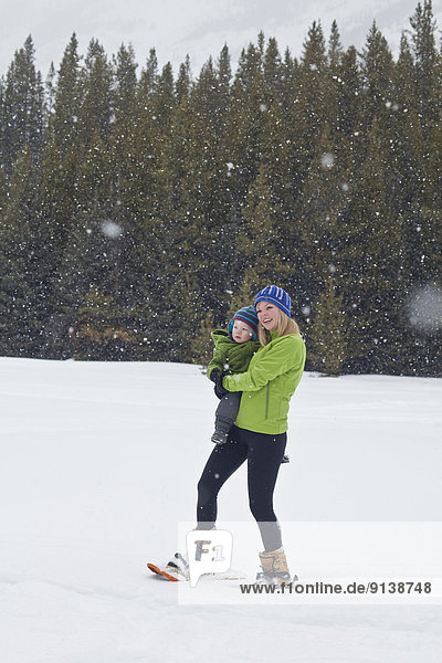 A young mother and baby son snowshoeing in Poccaterra  Peter Lougheed Park  Kananaskis  AB