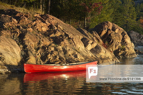 Red Canoe along a rocky shore on George Lake  Kilarney provincial park  Ontario