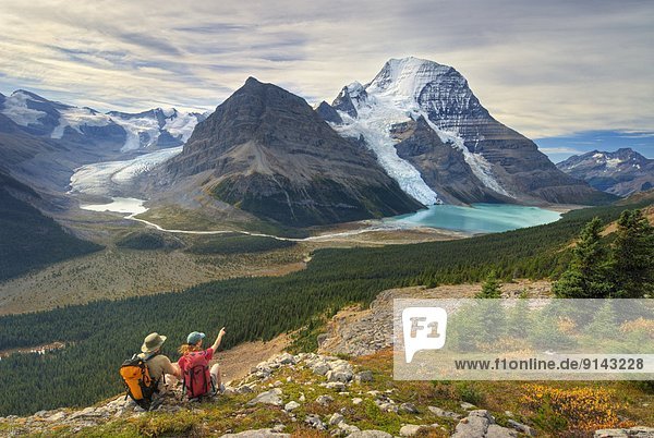 Two hikers  seated  looking at Mount Robson and Berg Lake  Mount Robson Provincial Park  British Columbia  Canada