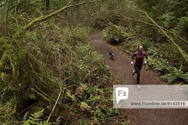 Woman trail running on the Capilano Pacific Trail  Capilano River Regional Park  North Vancouver  British Columbia  Canada