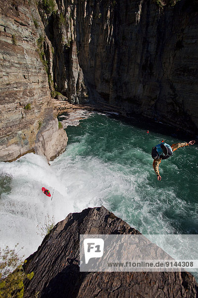 A male kayaker runs leap of faith  a 30 foot waterfall while a cliff jumper jumps from 70ft on the Upper Elk River  Fernie  BC