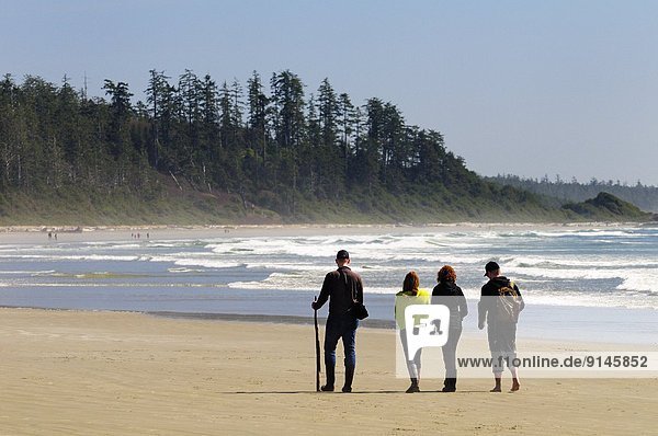 Four people walking along Long Beach in the Pacific Rim National Park near Tofino  BC.