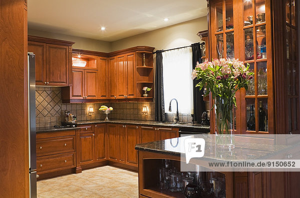 Kitchen room with wooden cabinets  marble countertops and ceramic tile floor inside a luxurious cottage style residential home  Montreal  Quebec  Canada. This image is property released. CUPR0194
