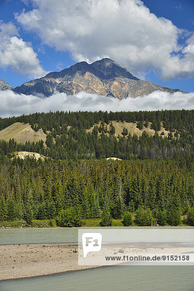 A vertical landscape of Pyramid mountain towering over the bench and the Athabasca river in Jasper National Park Alberta Canada.