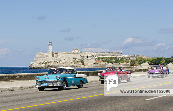 Vintage american cars alomg the Malecon  behind is Morro Castle  a picturesque fortress guarding the entrance to Havana bay  Havana  Cuba