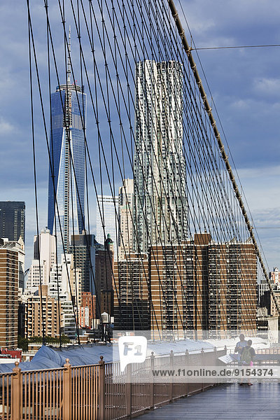 Lower Manhattan as seen through the cables that support the Brooklyn Bridge. The tallest buildings in the photograph are the New York by Gehry and the first (Tower 1) of several buildings that will make up the new World Trade Center complex. New York City  New York  U.S.A.