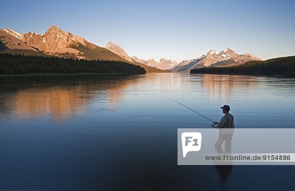 Middle age male fly fishing on Maligne Lake  Jasper National Park  Alberta  Canada.