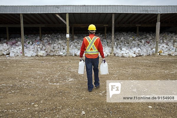 Worker sorting containers at pesticide recycling depot  Mountain View County  Alberta  Canada.