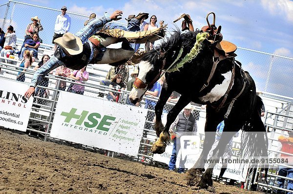 A cowboy gets some big air before landing on the ground after being bucked off his bare back horse at a rodeo event in Alberta Canada.