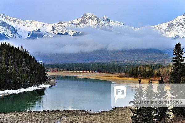 Swan Landing on the Athabasca river with snow-capped rocky mountains at Brule Alberta with a Canadian National freight train on the distant rail way tracks.