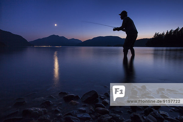 Man Fly fishing  sunset  Greenpoint  Harrison Lake near Harrison Hot Springs  British Columbia  Canada