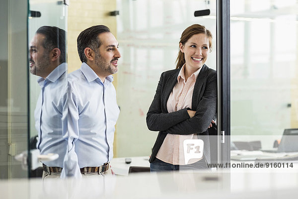 Lächelnde Geschäftsleute  die im Büro wegschauen