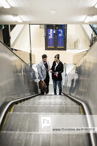 Volle Länge der Geschäftskollegen auf der Rolltreppe in der U-Bahn-Station