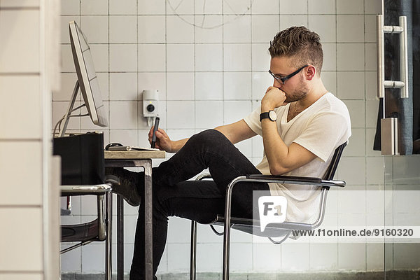 Side view of young businessman at computer desk in new office