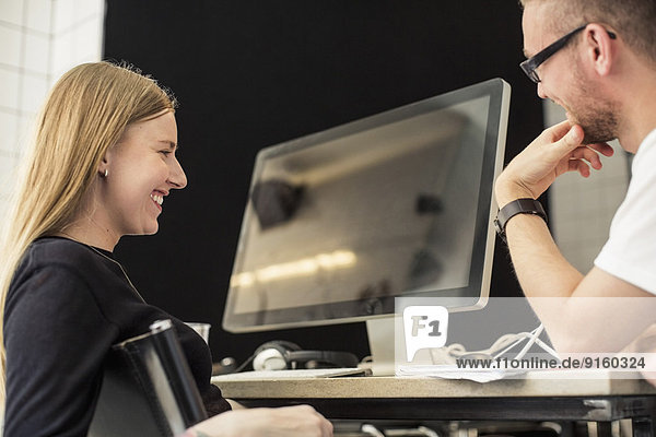 Junger Geschäftsmann und Geschäftsfrau beim Blick auf den Computermonitor im Kreativbüro