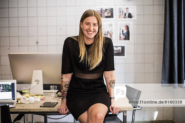 Portrait of smiling young businesswoman leaning at table in new office
