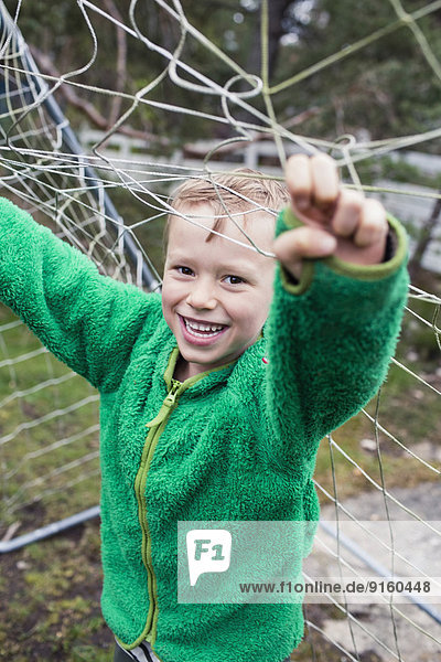 Porträt eines glücklichen Jungen mit Fußballnetz im Hof
