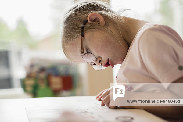 Mädchen mit Down-Syndrom beim Lernen am Tisch