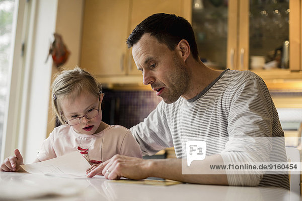 Father assisting handicapped daughter in studying at home