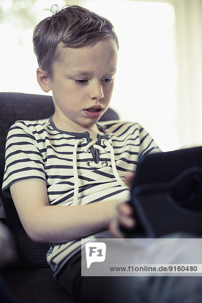 Junge mit digitalen Tablette auf Sofa