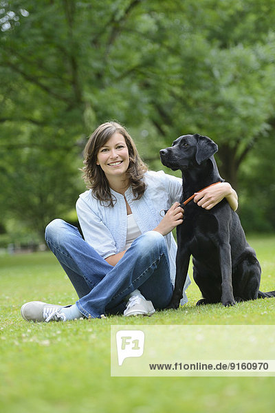 Frau mit einem schwarzen Labrador auf einer Wiese  Bayern  Deutschland  Europa