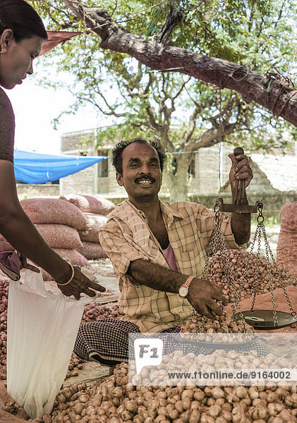 Fröhlicher Verkäufer mit Waage  indischer Markt  Chinnamanur  Tamil Nadu  Indien