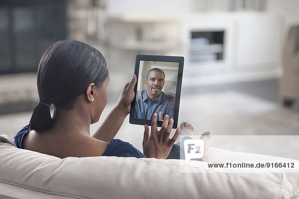 Woman video conferencing with father on digital tablet