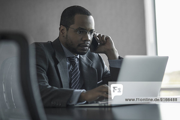 Mixed race businessman talking on cell phone at desk
