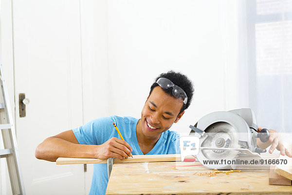 Mixed race carpenter marking wood