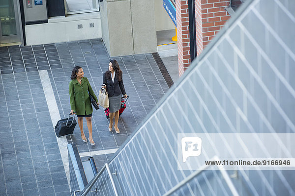 Businesswomen with suitcases near escalator
