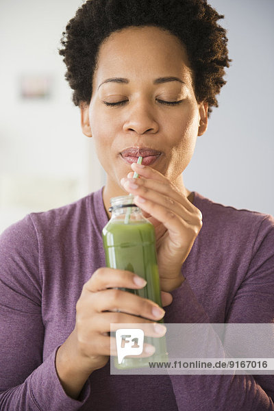 Close up of Black woman drinking green smoothie