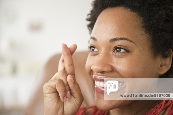 Close up of Black woman smiling with fingers crossed