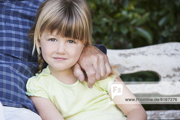 Caucasian girl sitting with grandfather on bench