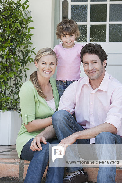 Caucasian family smiling on front steps
