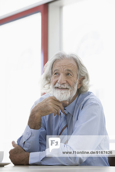 Senior Caucasian businessman smiling at desk