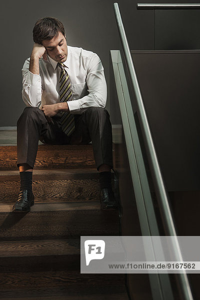 Stressed businessman sitting on stairs