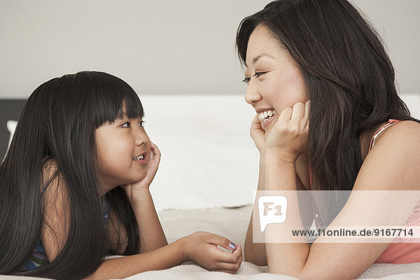Mother and daughter talking on bed