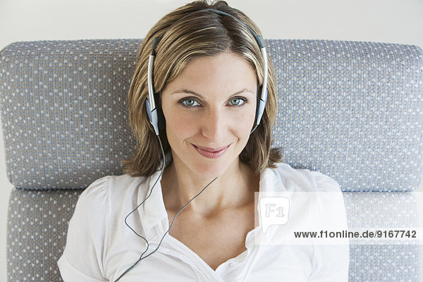 Woman listening to headphones in armchair