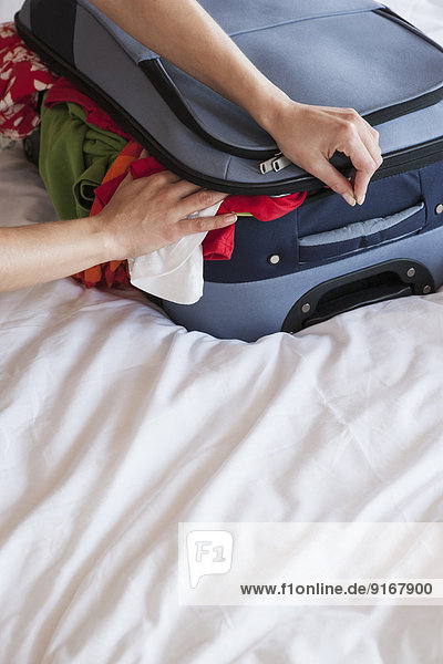 Woman packing suitcase on bed